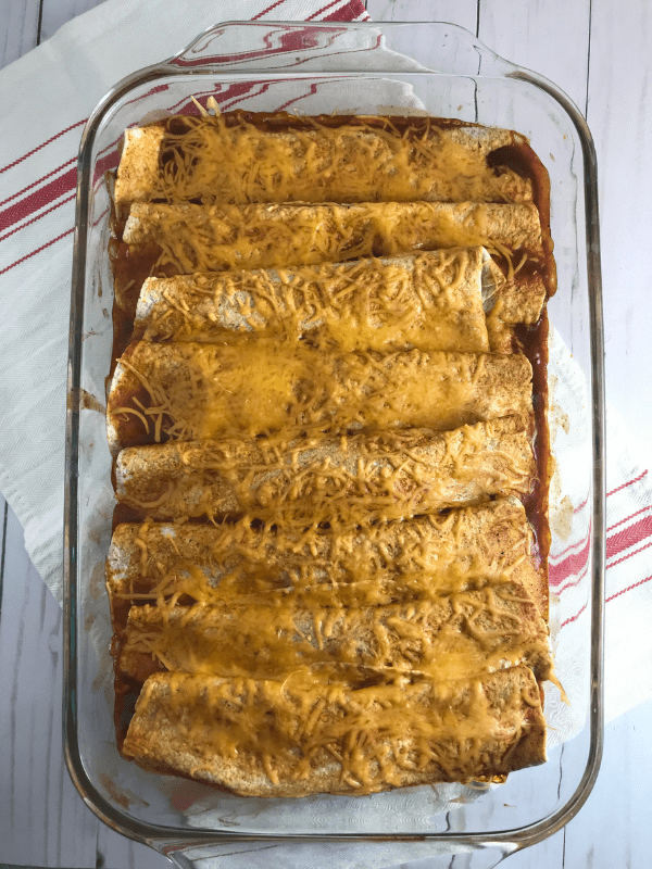 Lean ground beef, black beans, cream of mushroom soup, taco seasoning, salsa, enchilada sauce, onion, and jalapeño are cooked together and wrapped in a tortilla. Then the loaded tortillas are topped with enchilada sauce and cheese and baked until the tortillas become soft, the cheese is melted, and the inside meat mixture is nice and warm.