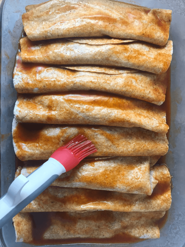 Use a basting brush to spread the enchilada sauce over the tops of the tortillas.