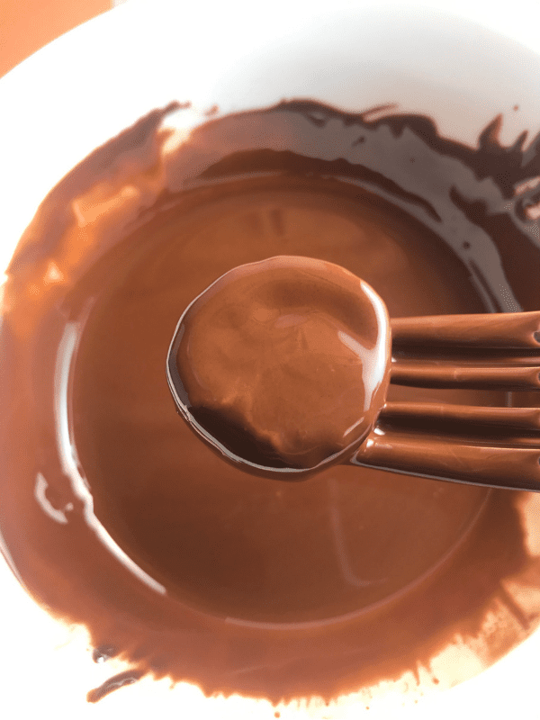 Use a fork to fully coat the banana bites with the chocolate mixture.